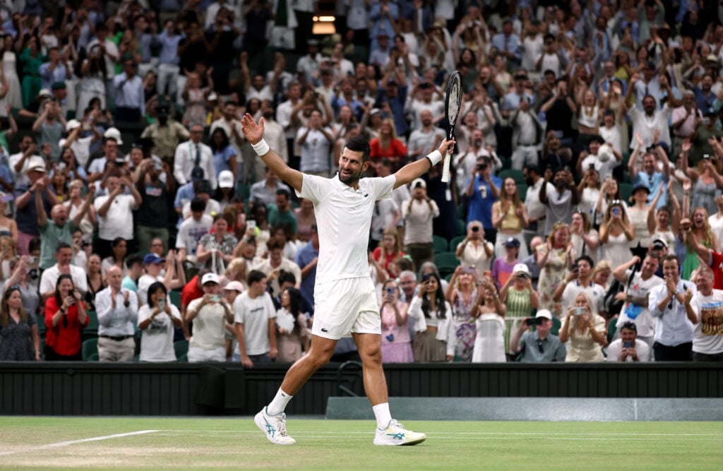 Novak Djokovic holds out his arms in celebration
